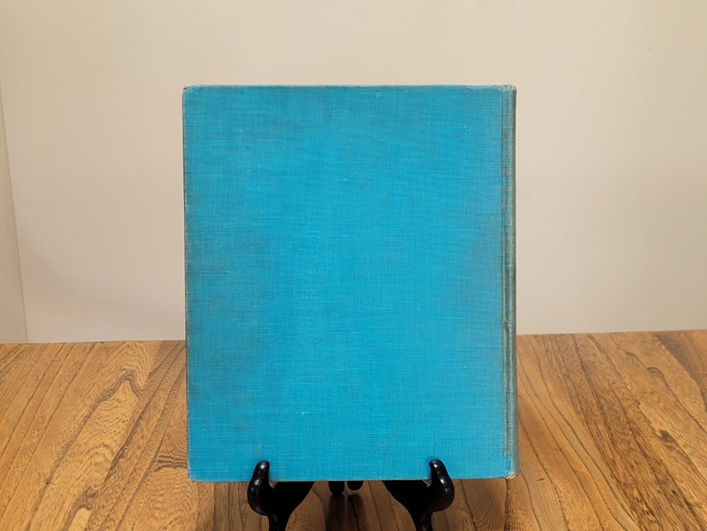 K&ouml;nnte beinhalten: Ein blaues Hardcover-Buch mit einem strukturierten Einband. Das Buch steht auf einer Holzoberfl&auml;che.