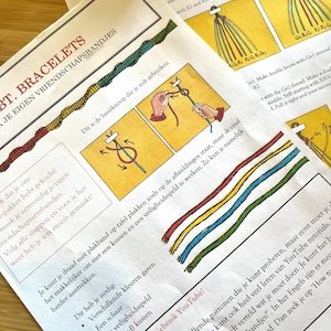 May include: A colorful instruction sheet for making friendship bracelets. The sheet includes a diagram of the basic knot, a list of materials needed, and instructions for making double knots. The text is in Dutch.