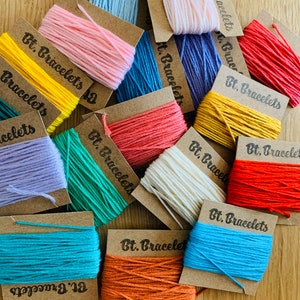 May include: Assortment of colorful embroidery floss spools on brown card stock with the text "Bt. Bracelets" on each card.