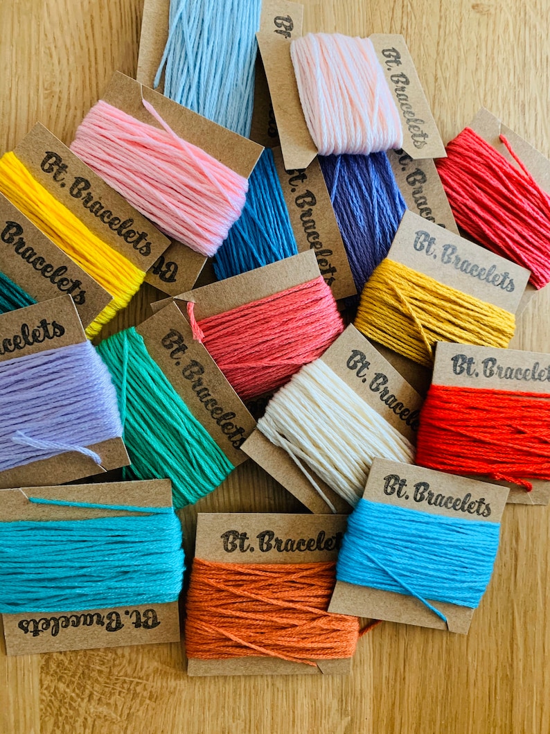 May include: Assortment of colorful embroidery floss spools on brown card stock with the text "Bt. Bracelets" on each card.