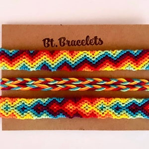 May include: Three colorful friendship bracelets on a brown card with the text "Bt. Bracelets". The bracelets are made with colorful threads in a chevron pattern and a braided pattern.