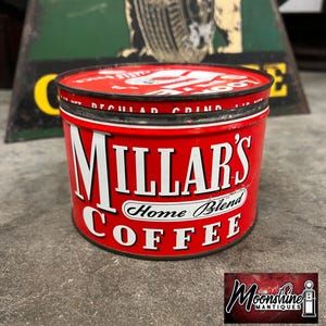 May include: A vintage red cylindrical metal coffee tin featuring the white text Millar's Home Blend Coffee on the side. The lid is also red with white text and a graphic design. The container has a dark metal rim and shows signs of age.