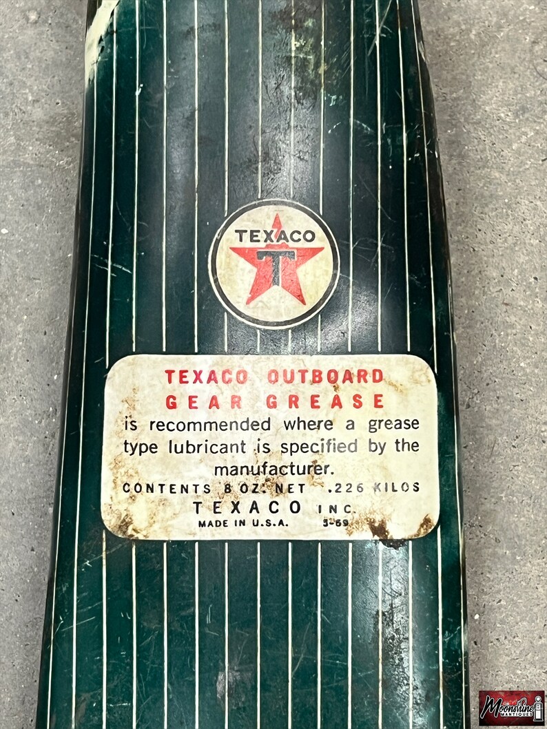 Puede incluir: Lata de grasa para engranajes fueraborda Texaco vintage. La lata es de color verde oscuro con rayas verticales blancas. El logotipo de Texaco es una estrella roja dentro de un c&iacute;rculo blanco. La etiqueta dice "TEXACO OUTBOARD GEAR GREASE" y "CONTENIDO 226 gramos".