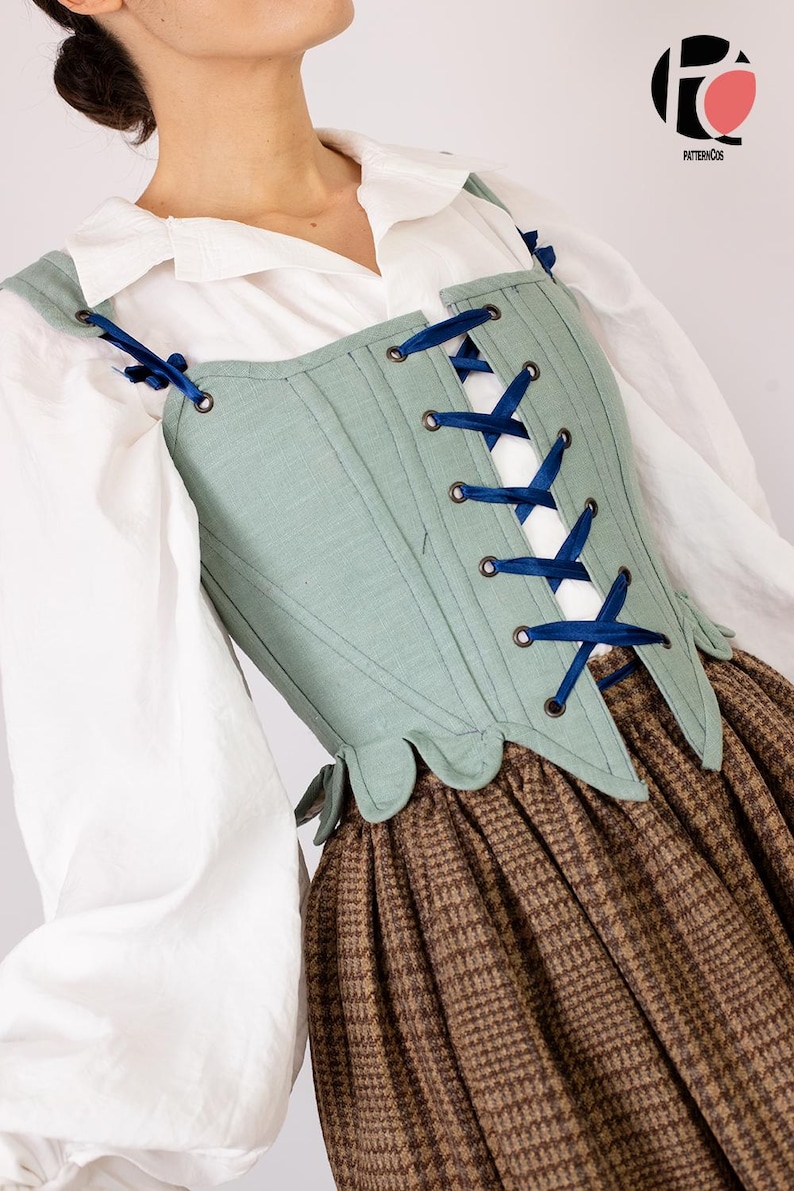 May include: A light green corset with dark blue ribbon lacing. The corset is worn over a white blouse and a brown plaid skirt. The corset has a scalloped edge and is part of a historical costume.