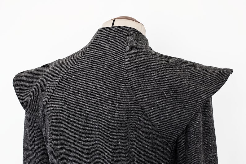 May include: A black and gray tweed jacket with a high collar and large shoulder pads.