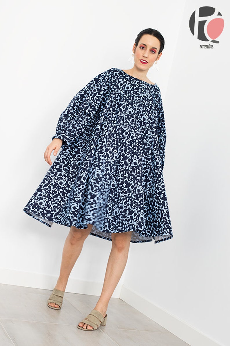 May include: A woman wearing a blue and white animal print dress with a loose fit and long sleeves. She is wearing beige heeled sandals.