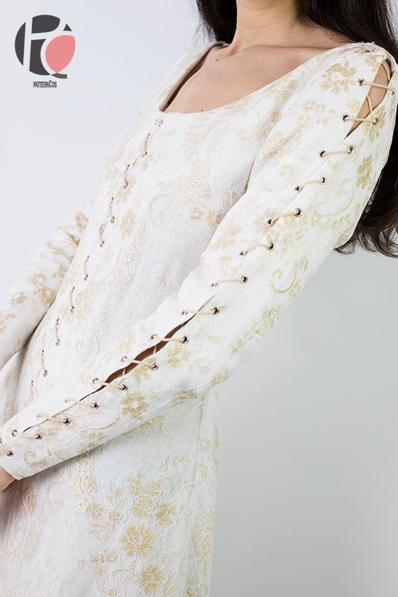 Peut inclure: Robe blanche en dentelle avec des broderies dor&eacute;es et des d&eacute;tails de la&ccedil;age sur les manches.