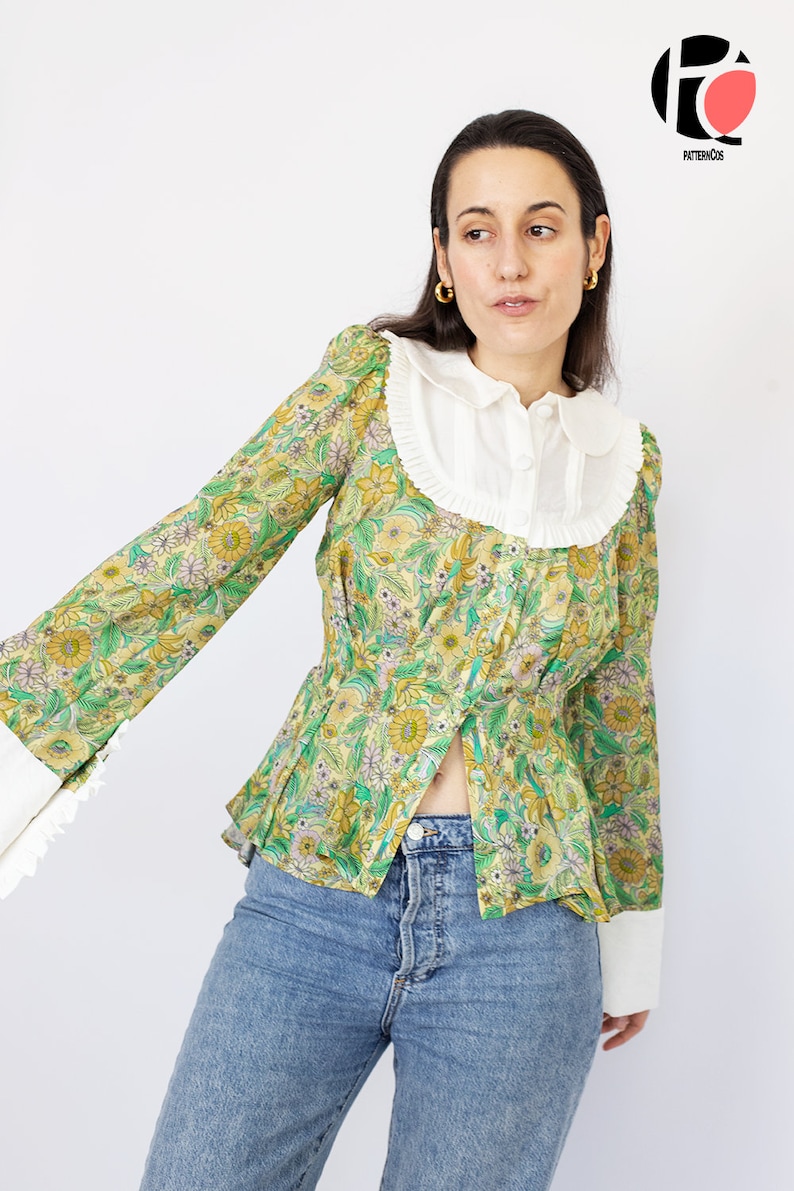 May include: A green and yellow floral print blouse with a white Peter Pan collar and long sleeves. The blouse has a fitted waist and a slightly flared hem.