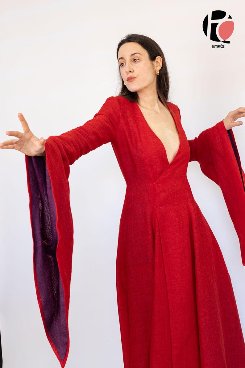 May include: A vibrant red dress with long, flowing sleeves and a deep V-neckline. The sleeves have a contrasting purple lining. The dress is made of a textured fabric and has a flared skirt. The image features the PatternCos logo in the upper right corner.