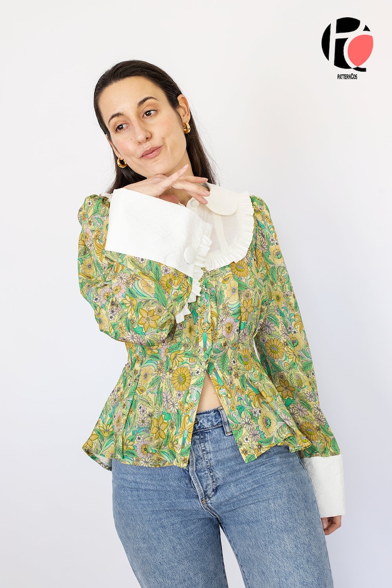 May include: A green and yellow floral print blouse with a white Peter Pan collar and white cuffs. The blouse has a fitted bodice and a slightly flared hem.