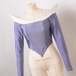 Peut inclure: Un corsage violet avec un col blanc et des manches longues. Le corsage est ajust&eacute; et a une taille pointue. Le corsage est sur un mannequin.