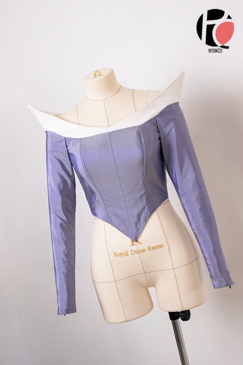 Peut inclure: Un corsage violet avec un col blanc et des manches longues. Le corsage est ajust&eacute; et a une taille pointue. Le corsage est sur un mannequin.