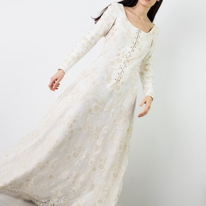 Peut inclure: Une robe en dentelle blanche &agrave; manches longues et &agrave; fermeture boutonn&eacute;e sur le devant. La robe a un col rond et une jupe ample.