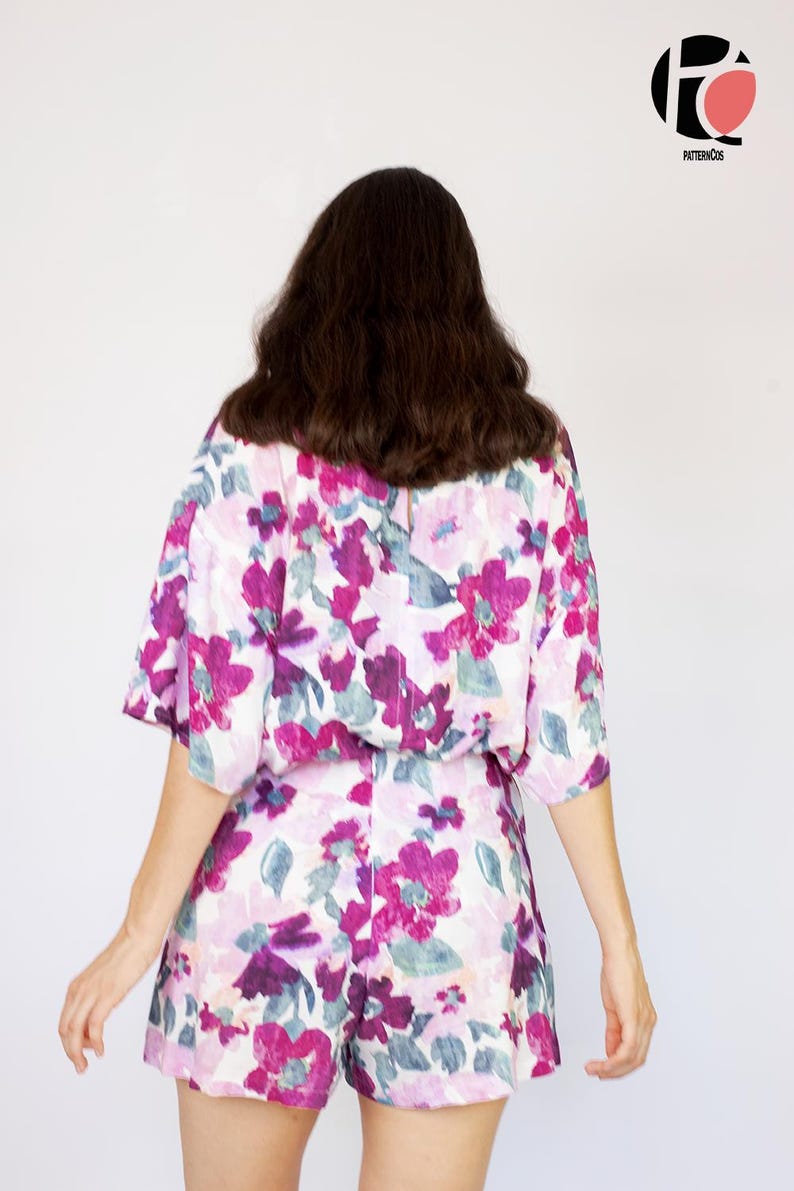 May include: A woman wearing a white and purple floral print short-sleeved top and matching shorts.