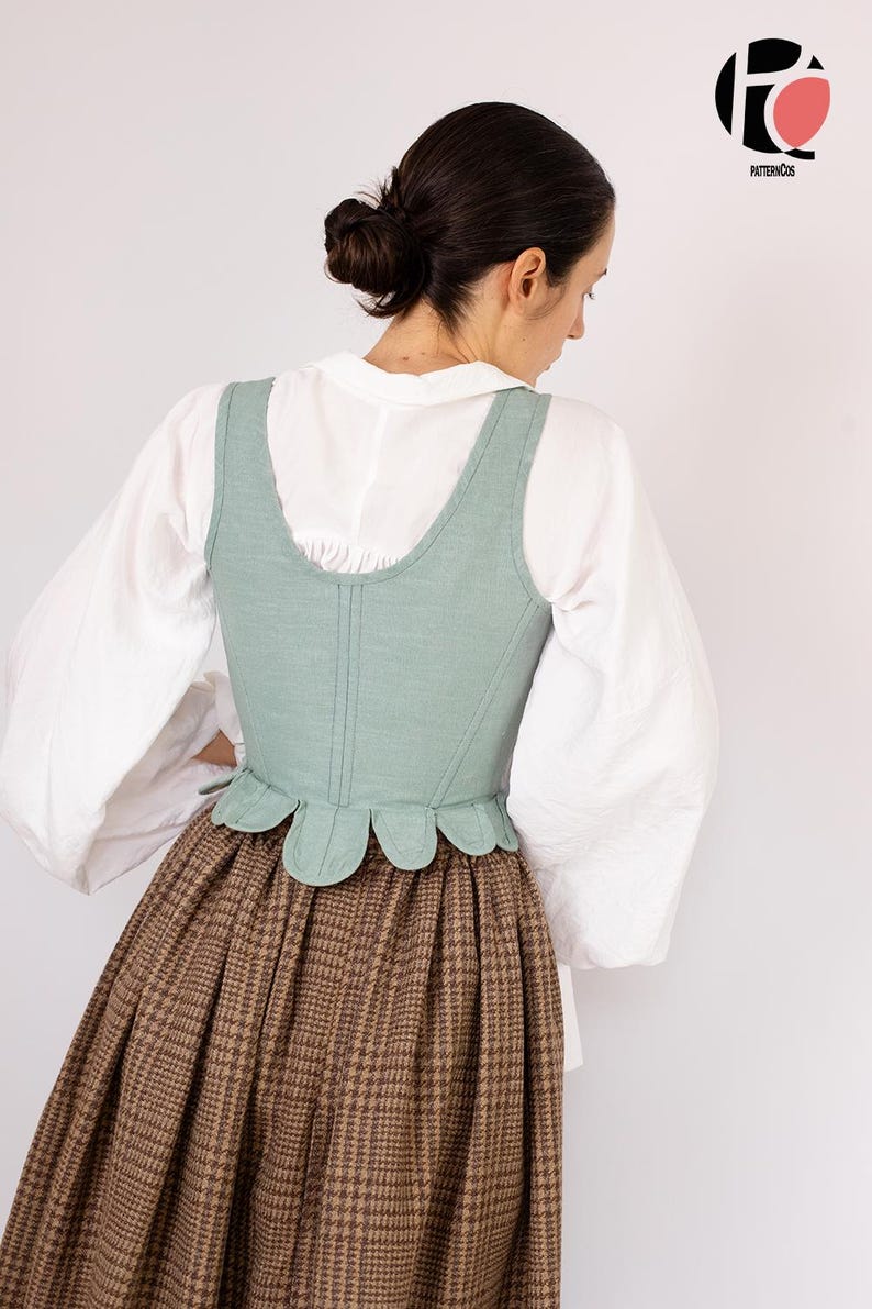 May include: A light green corset with a scalloped hem is worn over a white blouse with puffy sleeves. A brown plaid skirt completes the historical outfit. The image features the PatternCos logo in the upper right corner.