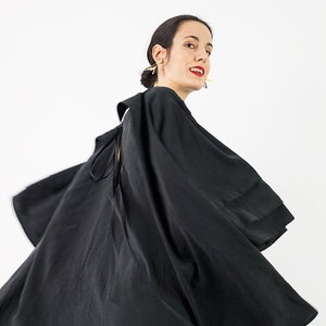 May include: A black dress with a flowing skirt and a tie at the back. The dress is made of a soft, silky fabric.