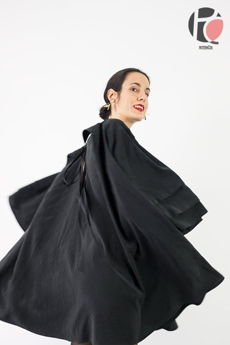 May include: A black dress with a flowing skirt and a tie at the back. The dress is made of a soft, silky fabric.