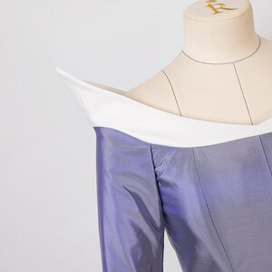 Peut inclure: Un corsage violet avec un col blanc et des manches longues. Le corsage est sur un mannequin.