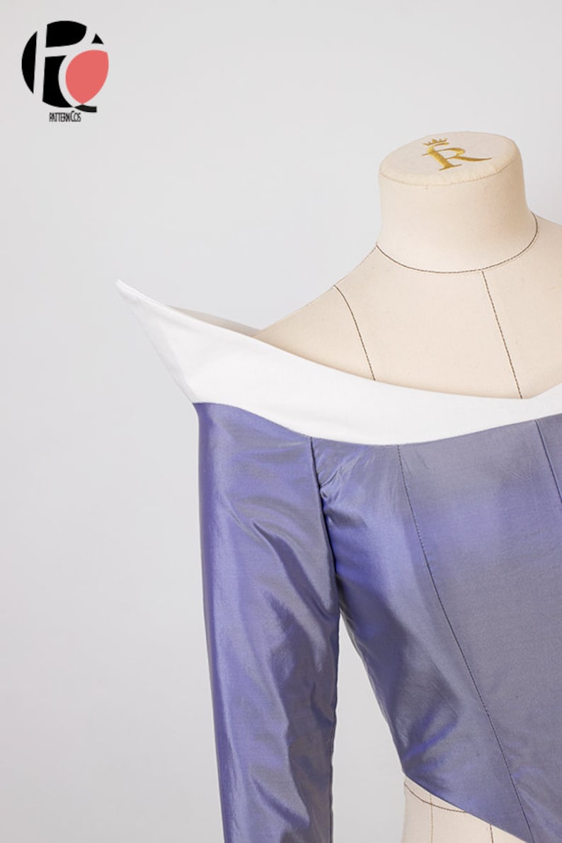 Peut inclure: Un corsage violet avec un col blanc et des manches longues. Le corsage est sur un mannequin.