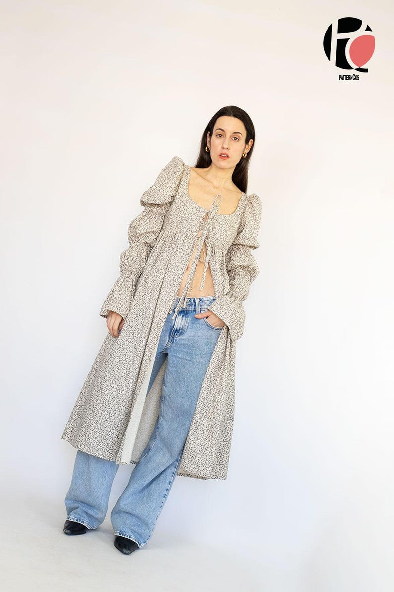 May include: A long, open-front dress with a floral pattern, featuring a square neckline and puffed sleeves. The dress is paired with light blue jeans. The image also includes a logo in the upper right corner.