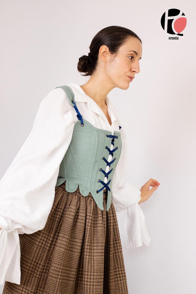 May include: A light green corset with blue lacing and straps is worn over a white blouse and a brown plaid skirt. The corset has a scalloped edge. The outfit is reminiscent of historical fashion.