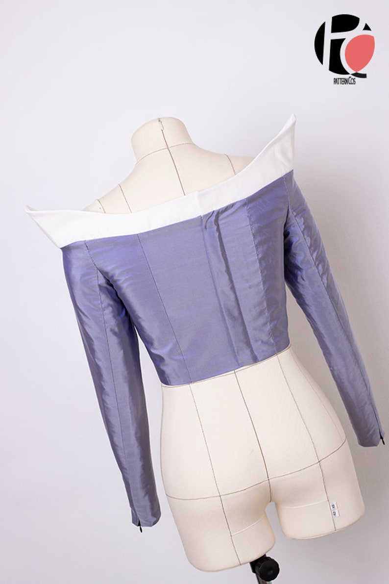 Peut inclure: Un haut violet &agrave; &eacute;paules d&eacute;nud&eacute;es avec un col blanc et des manches longues. Le haut est sur un mannequin blanc.