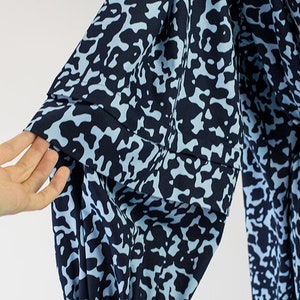 May include: Close-up of a blue and white patterned fabric sleeve with a gathered puff detail. The fabric has a camouflage-like print.