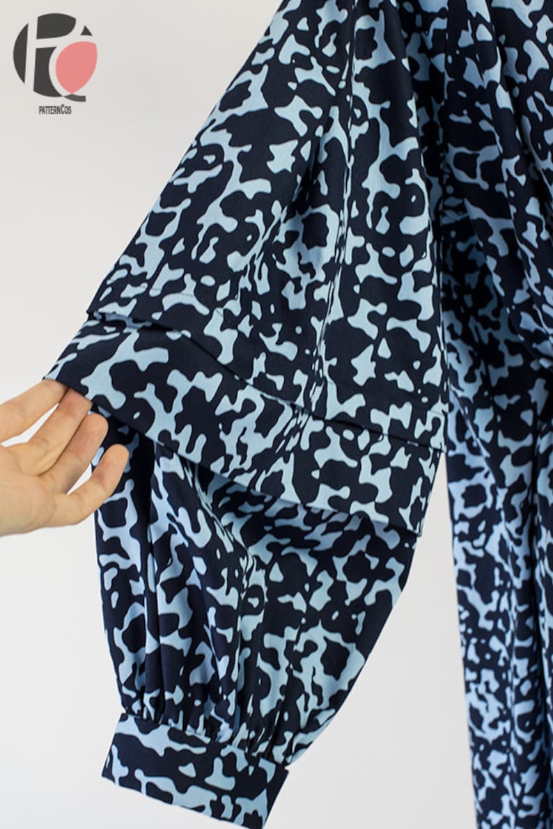 May include: Close-up of a blue and white patterned fabric sleeve with a gathered puff detail. The fabric has a camouflage-like print.