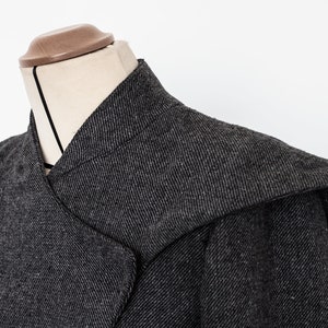 May include: A gray hooded jacket with a unique collar design. The jacket is made of a textured fabric and has a relaxed fit.