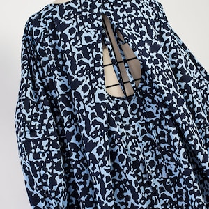May include: A blue and black patterned dress with a tie at the back. The dress has a loose fit and 3/4 sleeves.