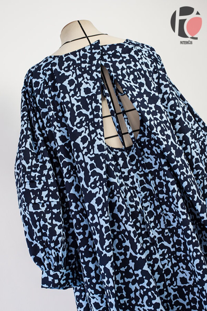 May include: A blue and black patterned dress with a tie at the back. The dress has a loose fit and 3/4 sleeves.