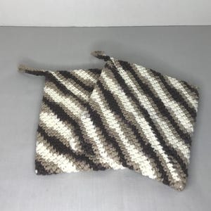 May include: Two crocheted pot holders in a brown and white striped pattern.