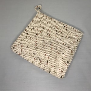 May include: A crocheted pot holder with a cream background and brown and green flecks. The pot holder has a loop for hanging.