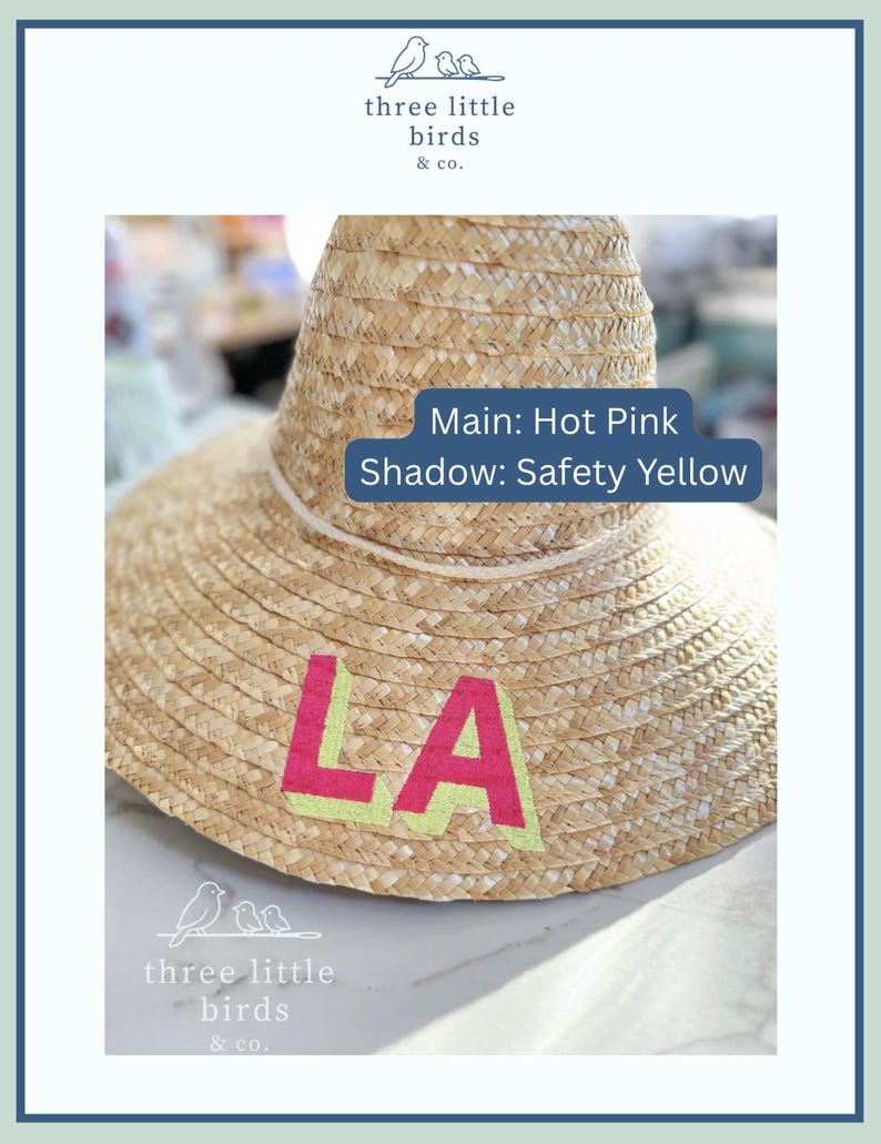 May include: A woven straw hat featuring the letters LA in hot pink with a safety yellow shadow. A white cord encircles the base of the crown. Text on the image reads: Main: Hot Pink, Shadow: Safety Yellow, and the logo for three little birds & co.