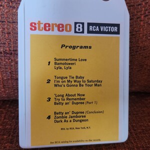 May include: A white plastic 8-track tape cartridge with a yellow label featuring the text stereo 8, RCA Victor, and a tracklist including Summertime Love, Bamotsweri, Lyla, Lyla, Tongue Tie Baby, I'm on My Way to Saturday, Who's Gonna Be Your Man, 'Long About Now, Try to Remember, Betty an' Dupree, Zombie Jamboree, and Dark As a Dungeon.