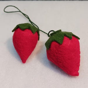 May include: Two felt strawberry ornaments with green felt leaves and a string for hanging.