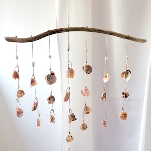 Peut inclure: Mobile d&eacute;coratif fait &agrave; la main, compos&eacute; d'une branche de bois flott&eacute; et de coquillages suspendus. Les coquillages, de diff&eacute;rentes tailles et couleurs, sont attach&eacute;s avec de la ficelle et des perles blanches. Pour l'int&eacute;rieur.