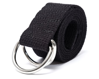 Könnte beinhalten: Aufgerollter schwarzer Yoga-Gurt mit zwei silbernen D-Ringen aus Metall. Der Gurt besteht aus einem gewebten Stoff und ist für Dehn- und Flexibilitätsübungen konzipiert. Der Hintergrund ist weiß.