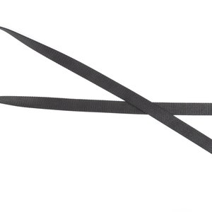 K&ouml;nnte beinhalten: Ein schwarzes Nylonband mit einem silbernen D-Ring aus Metall.