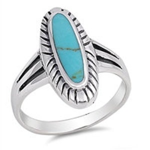 May include: A silver ring with an oval turquoise stone set in a detailed silver bezel. The ring has a textured band with three raised lines.