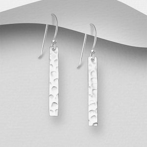 May include: Silver dangle earrings with a hammered bar design. The earrings are simple and elegant.