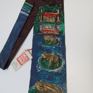 Puede incluir: Una corbata de seda azul y marrón con un logotipo de Budweiser y tres ranas en un nenúfar. La corbata tiene una etiqueta roja que dice "Know When to Say When."