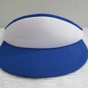 Puede incluir: Una visera azul y blanca con un panel frontal blanco y una visera azul.