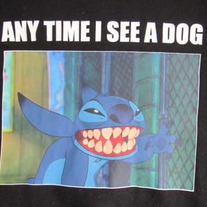 Peut inclure: T-shirt noir avec une image de dessin anim&eacute; de Stitch de Lilo & Stitch. Le personnage bleu sourit avec un grand sourire et le texte "ANY TIME I SEE A DOG" est imprim&eacute; au-dessus de l'image en blanc.