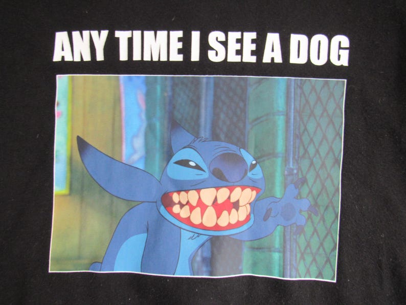 Peut inclure: T-shirt noir avec une image de dessin anim&eacute; de Stitch de Lilo & Stitch. Le personnage bleu sourit avec un grand sourire et le texte "ANY TIME I SEE A DOG" est imprim&eacute; au-dessus de l'image en blanc.