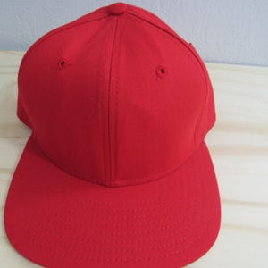 May include: A solid red baseball cap with a curved brim.