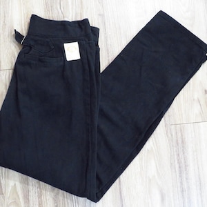 May include: A pair of black pants with a straight leg design. The pants are folded and have a tag attached. The fabric appears to be a soft material. The pants are lying on a light wood grain surface.