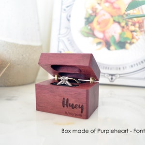 May include: A small wooden ring box made of purpleheart wood with a hinged lid. The box is engraved with the name "Husky" and the date "11/02/2019".