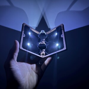 May include: A wooden ring box with a black velvet interior and a ring inside. The box is lit from the inside with small LED lights.