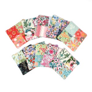 May include: A collection of rectangular fabric coasters featuring a variety of colourful floral, botanical, and fruit patterns. Each coaster is constructed from multiple quilted fabric patches in shades of red, pink, blue, green, and white.